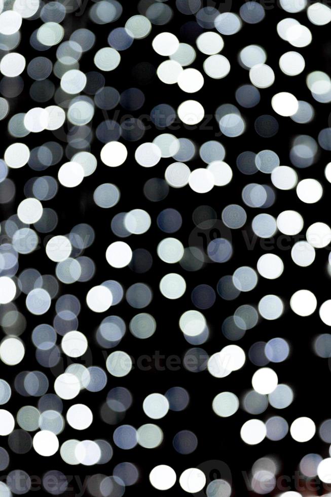 Bokeh blanco abstracto desenfocado sobre fondo negro. desenfocado y borroso muchas luces redondas foto