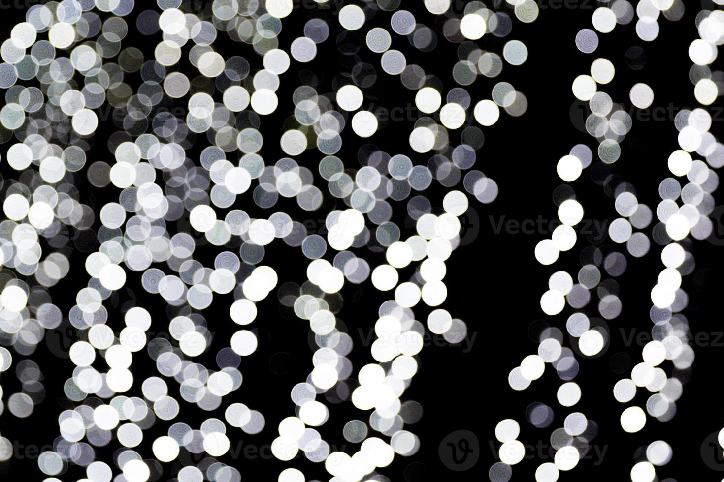 Unfocused abstract white bokeh on black background. defocused and blurred many round light photo