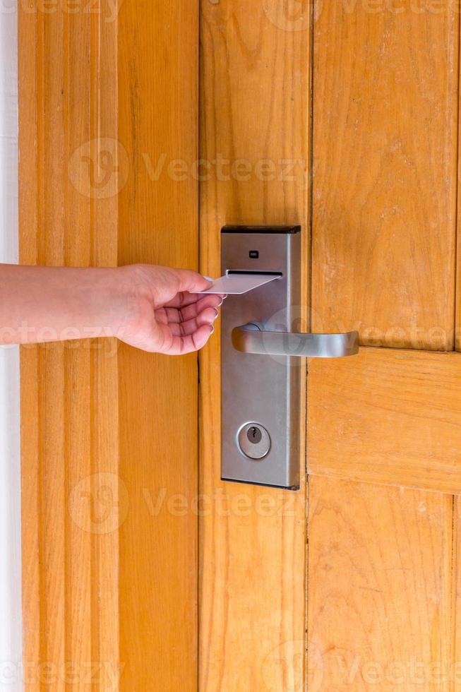 primer plano de la mano femenina sujetar la tarjeta llave y abrir la puerta de la cerradura electrónica foto