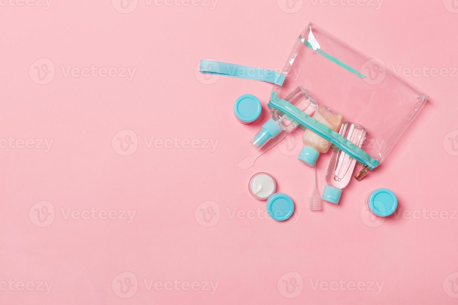 Top view of means for face care bottles and jars of tonic, micellar cleansing water, cream, cotton pads on pink background. Bodycare concept with empty cpace for your ideas photo