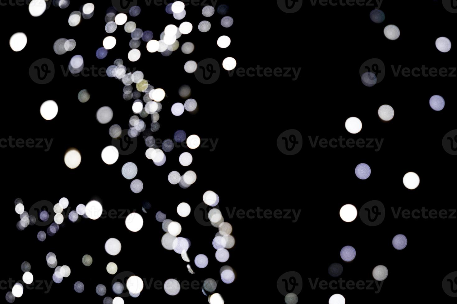 Unfocused abstract white bokeh on black background. defocused and blurred many round light photo