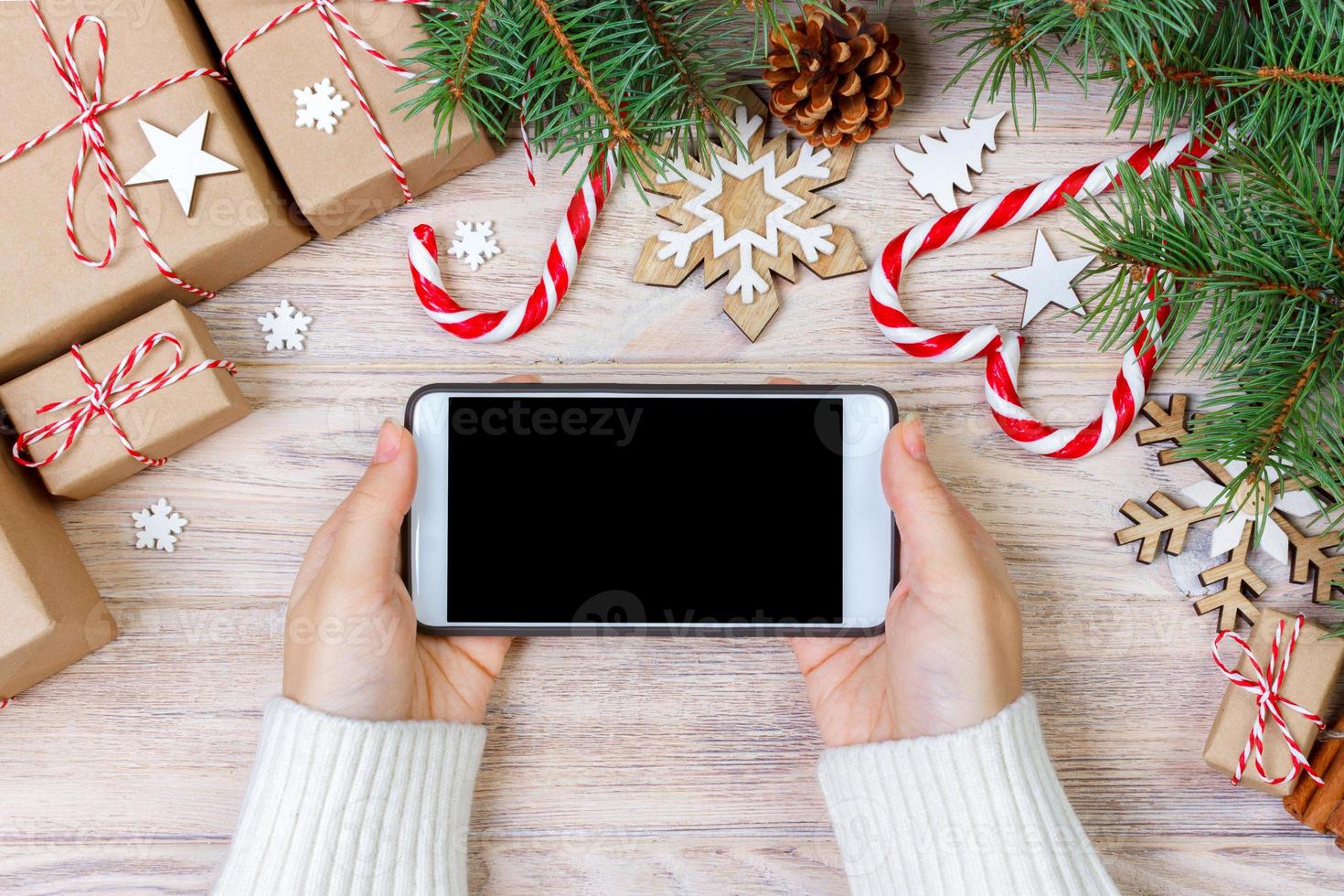 mujer que usa un teléfono inteligente con pantalla en blanco, marco festivo trumpery. búsqueda de regalos de navidad, compras en línea, descuentos de temporada y concepto de venta foto