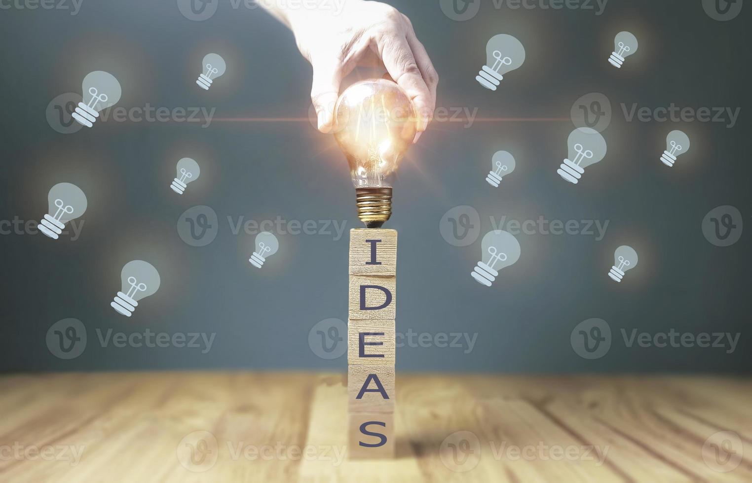 hand touching on light bulb on wood block with Word Ideas, new idea concept with innovation and inspiration, innovative technology in science and communication concept. photo