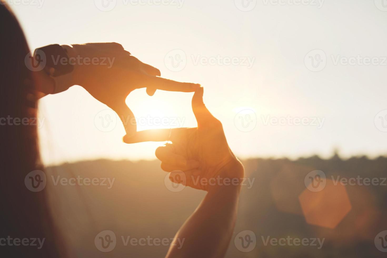 concepto de planificación y visión del comienzo del año nuevo, manos de mujer haciendo gestos de marco para encontrar el foco al atardecer, mujer buscando perspectiva para capturar el significado de un próximo objetivo claro. foto