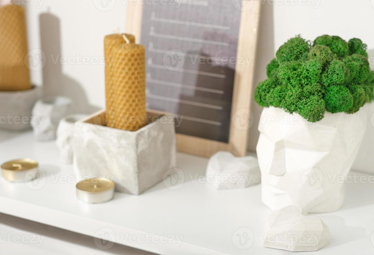 modern trendy loft house decor, beeswax candles, concrete boxes and vases with natural green moss. tea candles and cement accessories. minimal scandinavian style decoration. photo