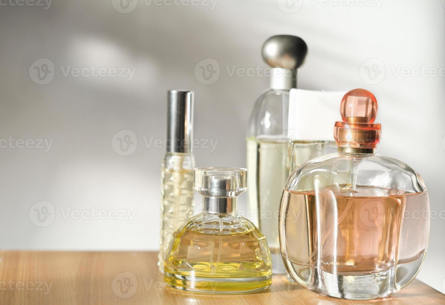 varios perfumes de mujer sobre fondo claro con sombras. enfoque selectivo en la botella delantera foto