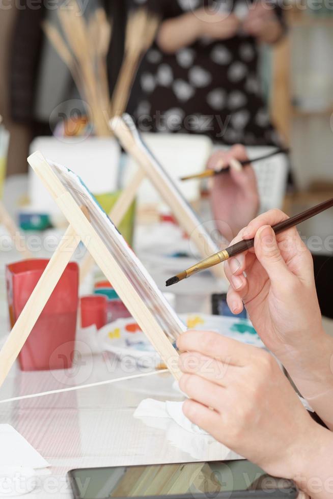 Cropped image of artist woman's hand drawing an acrylic color on canvas by paint brush at the modern art studio. photo