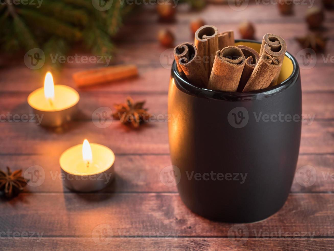 Black ceramic Cup with cinnamon on dark wooden table with candles photo
