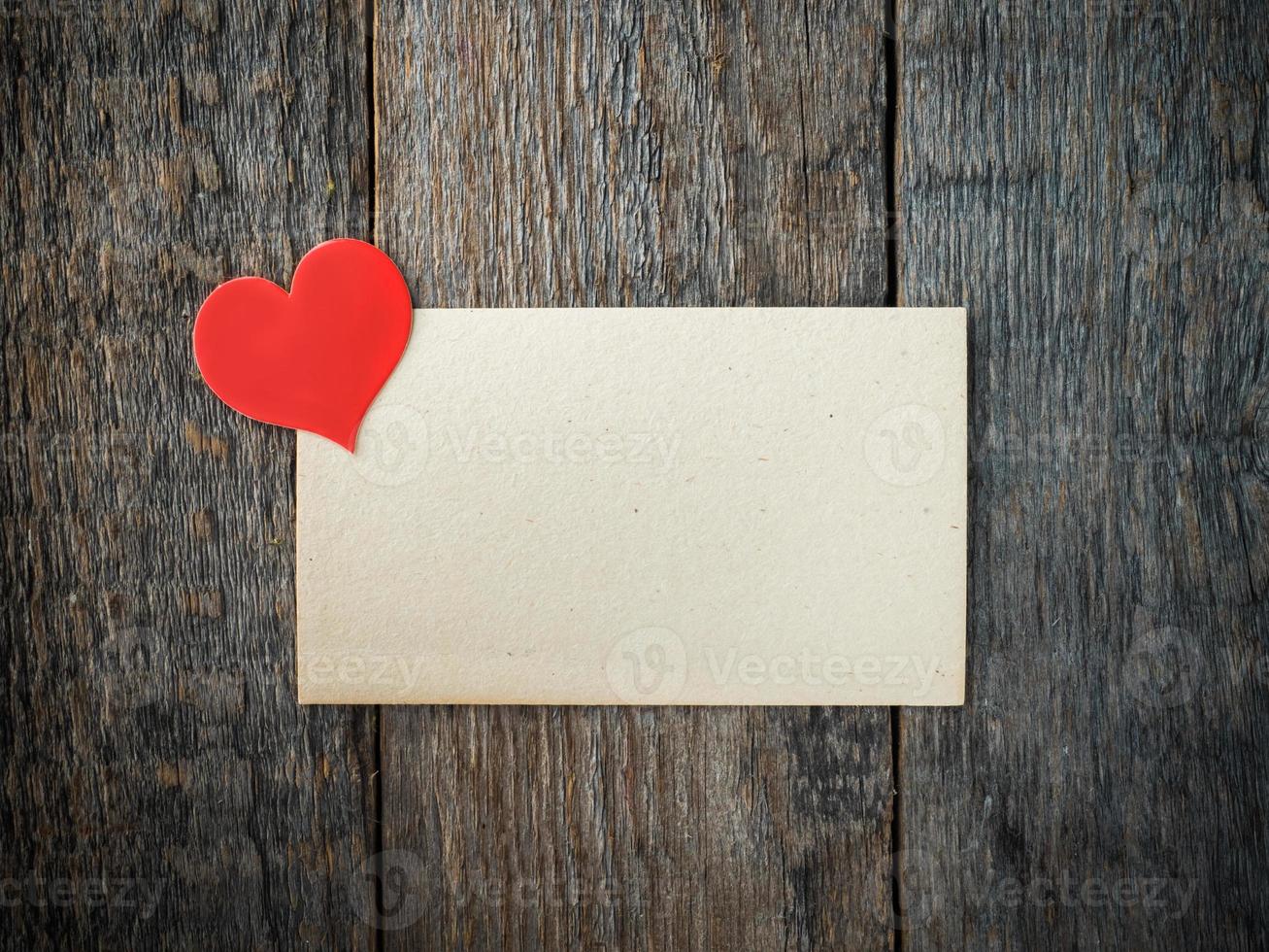 Paper heart on an old sheet of paper on rustic wooden background photo