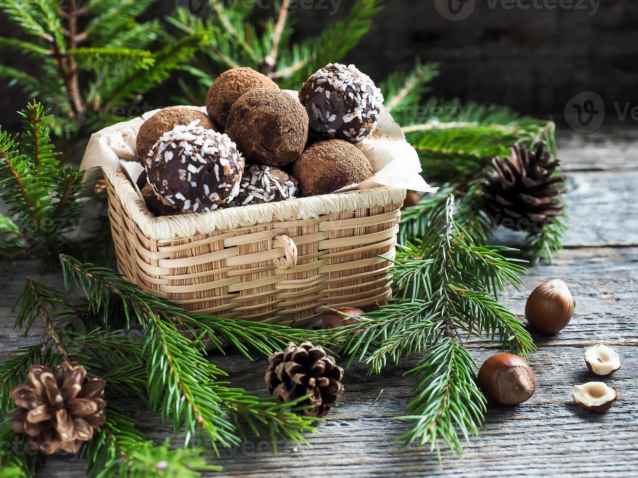 Christmas chocolate truffles in a wicker box the fir tree branches on wooden table photo