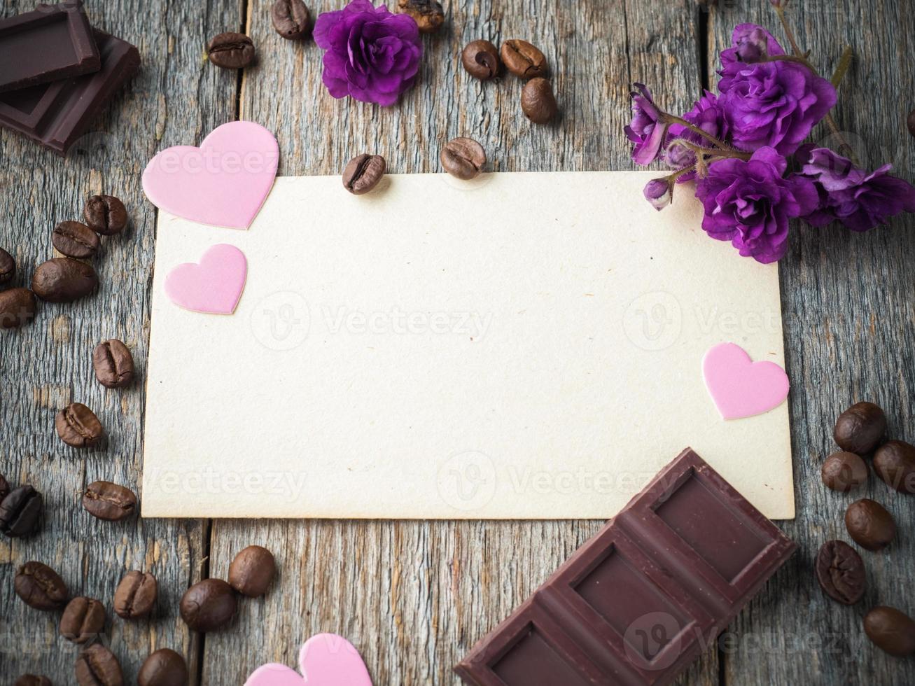 Decorations for Valentines day paper hearts, violets, coffee and chocolate on the old paper and wood background photo