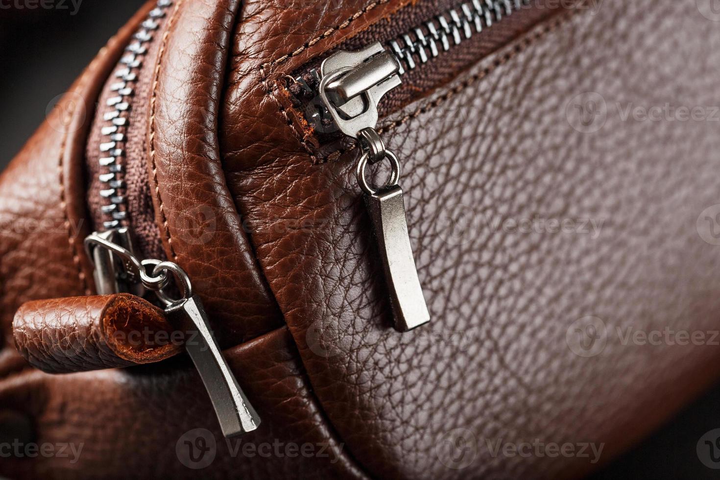 A brown belt bag made of textured brown leather on a black stone background. Elegant fanny pack brown bag with a zipper photo