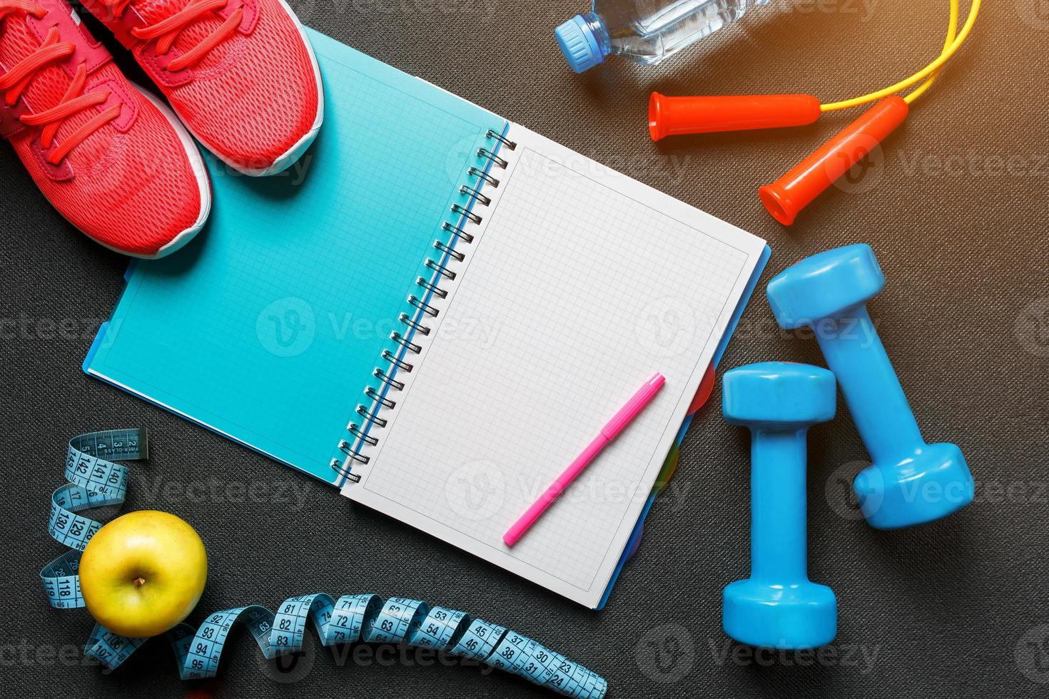 Notepad, a bottle of water, an apple, a skipping rope, dumbbells. Healthy diet, lifestyle, concept of dumbbells, exercise photo