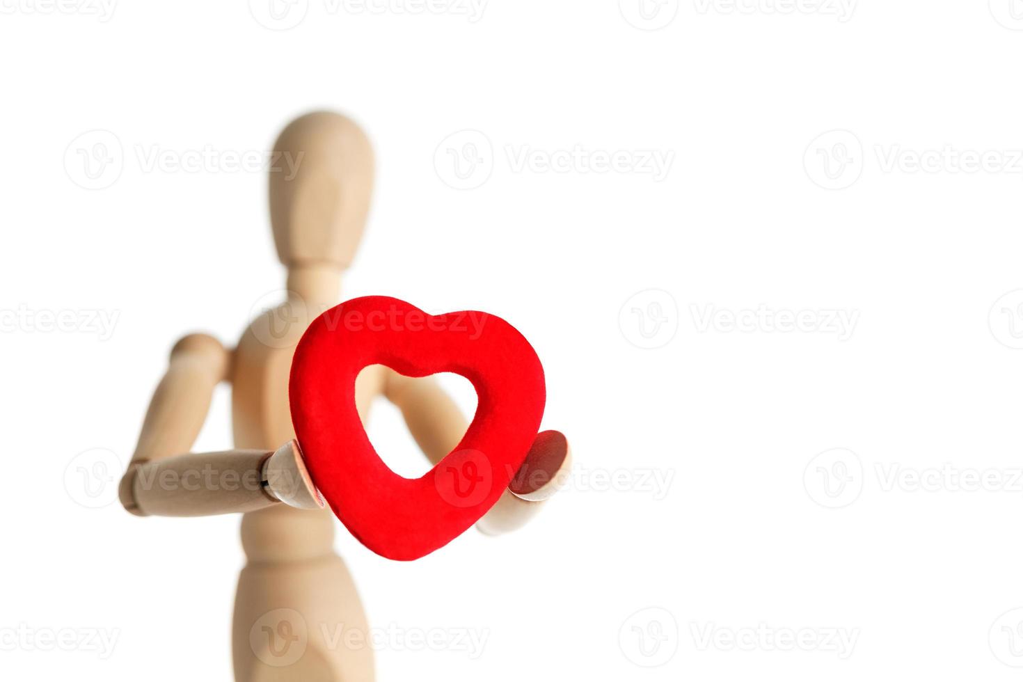 The wooden figure of a man holds in his hands a red heart on a white background. Gives the heart photo