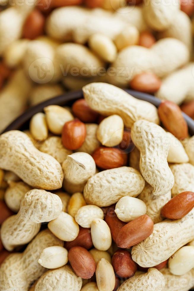 Peanuts in the shell and peeled close-up in cups. Roasted peanuts in their shells and peeled against a brown cloth. photo