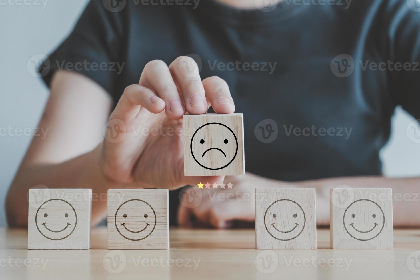 Sadness emotion, World mental health day, Mental health assessment, Customer experience, satisfaction survey, Feedback rating and service review. Hand holding sad face with 1 star from happy faces. photo