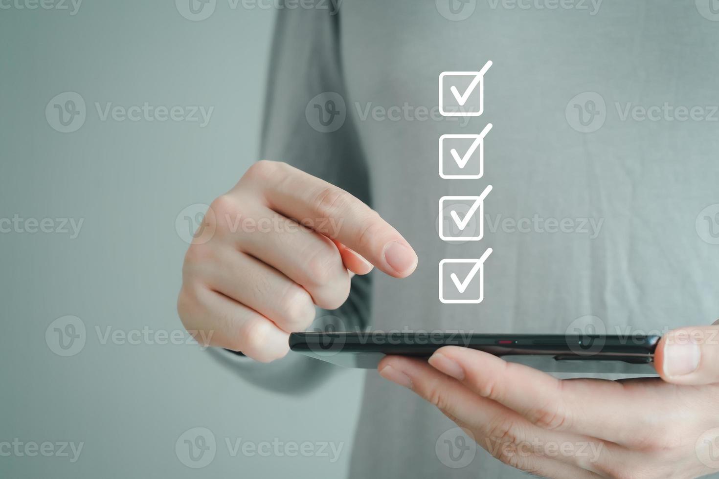 Checklist, Task list, Survey and assessment, Quality Control, Goal achievement and business success. Elections and Voting, Vote. Hand using mobile smartphone and check mark on checkbox for to do list. photo