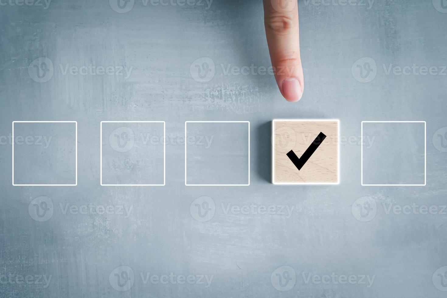 Elections and Voting, Vote, to do list, checklist, Task list, Survey and assessment concept. Hand holding check mark on wooden block and blank check box on wooden cubes. photo