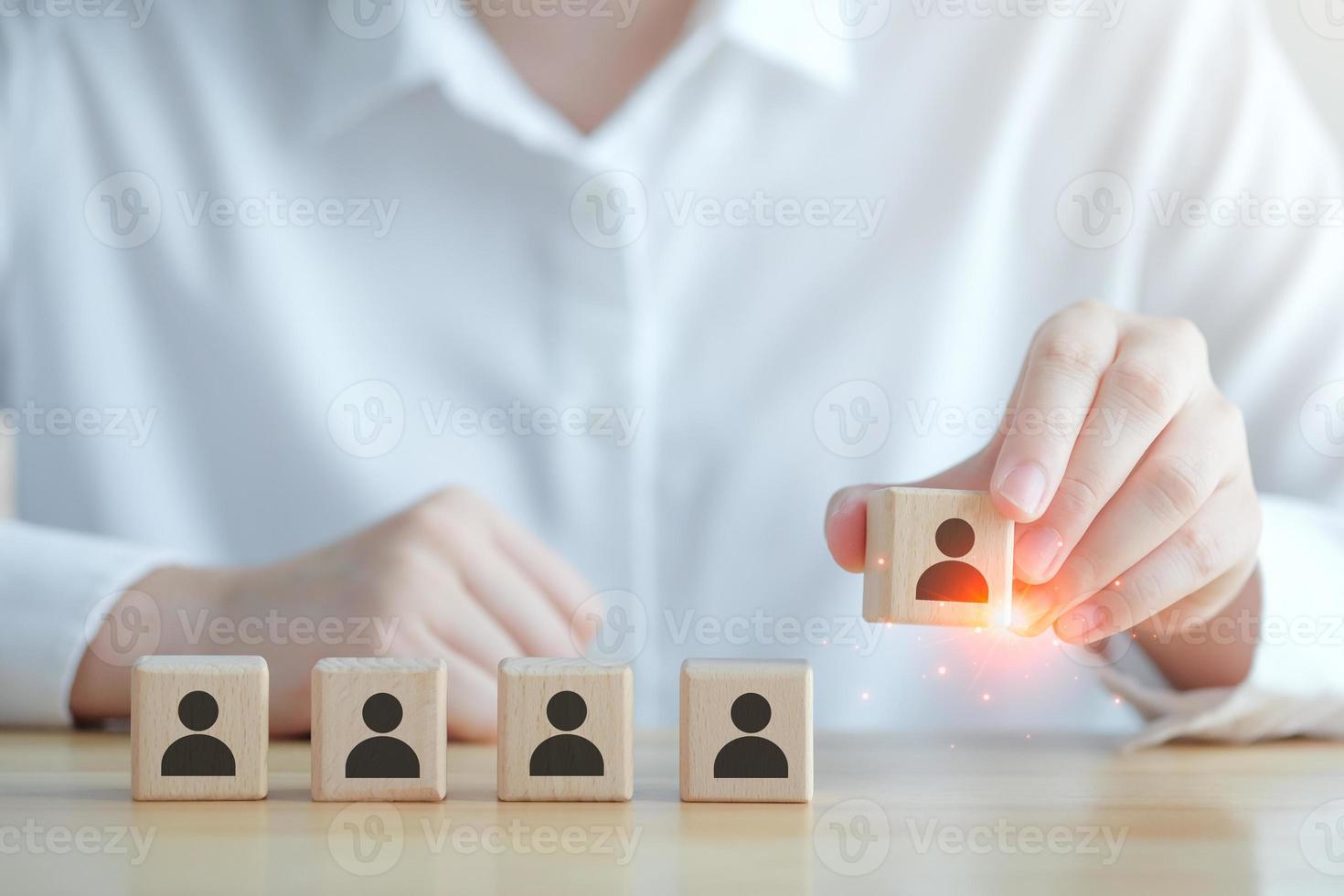 Business hiring and recruitment selection. Career opportunity. Human Resource Management. Hand choosing human icon on wooden block. Choice of employee leader or new employee from the crowd. photo