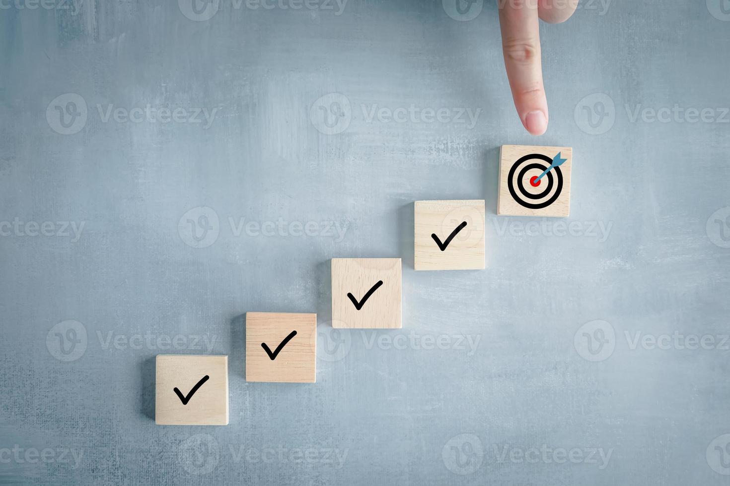 Checklist, Task list, Survey and assessment, Quality Control, Goals achievement and business success. To do list. Hand point to dartboard from top of step of complete with check mark on wooden block. photo