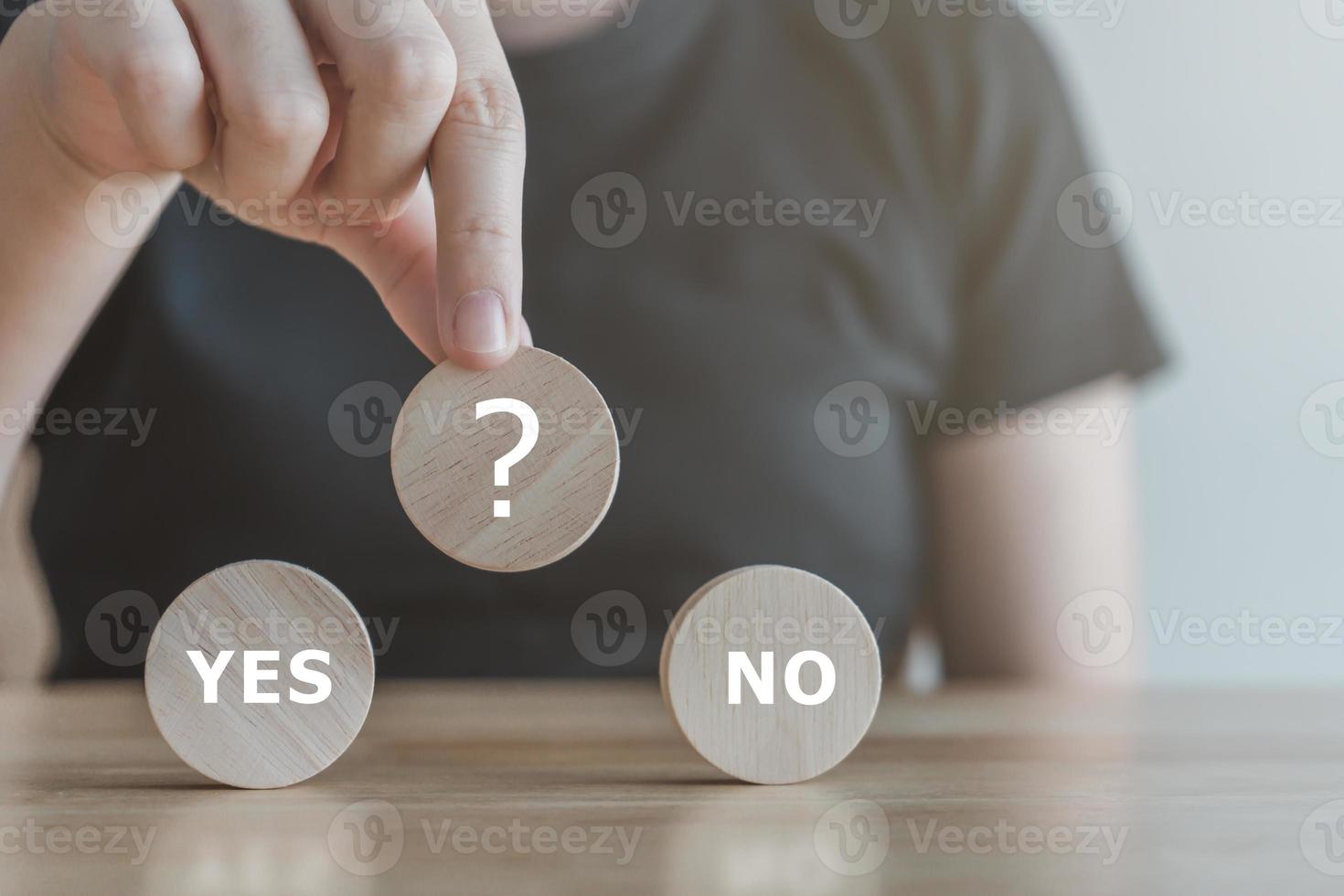 Think with Yes Or No choice.Test question. Choice hesitate, opposition, opponent view. making decision. Woman hand holding question mark on wooden circle with YES and NO text. photo