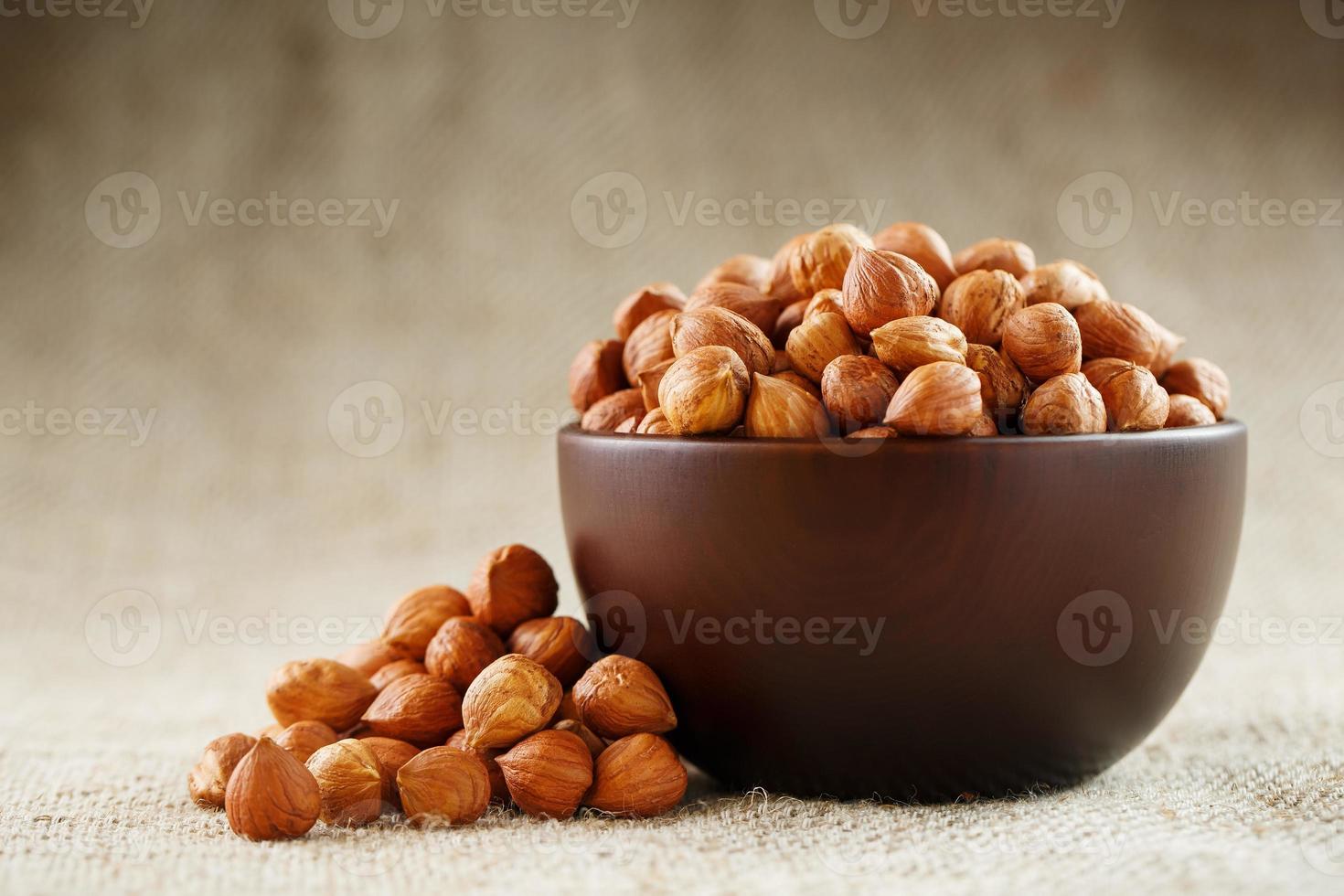 Peeled hazelnuts in a wooden, dark brown cup on a burlap cloth. Super Food, Raw. photo