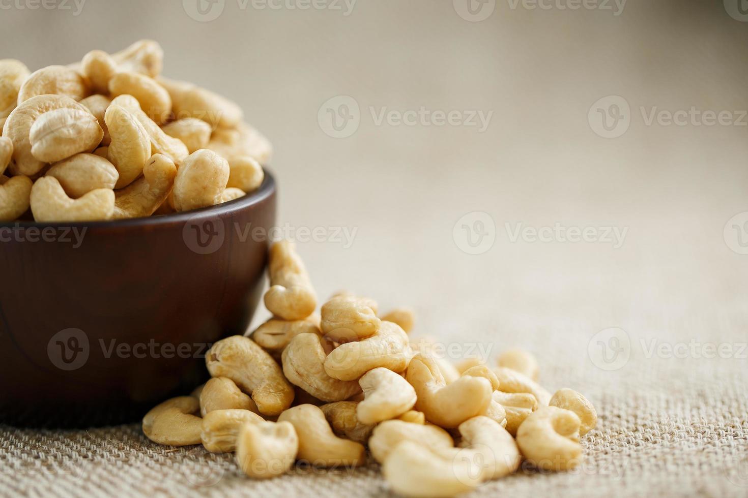 Cashew nuts in a wooden bowl on a burlap cloth background. photo