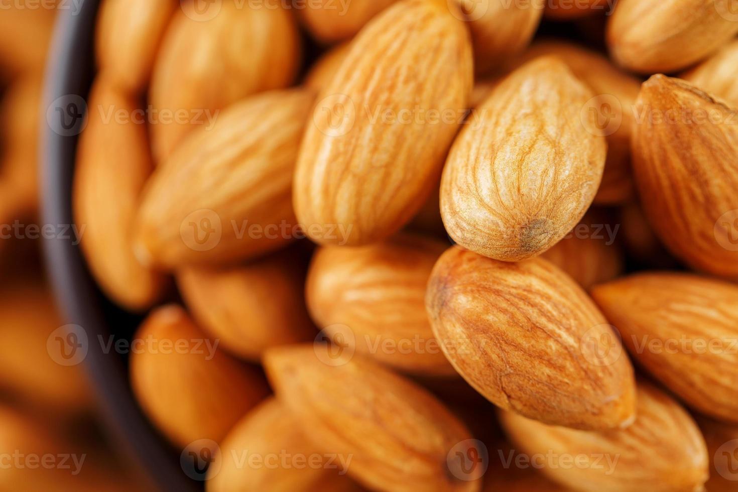 almendras en una taza de madera sobre un fondo de tela de arpillera. foto