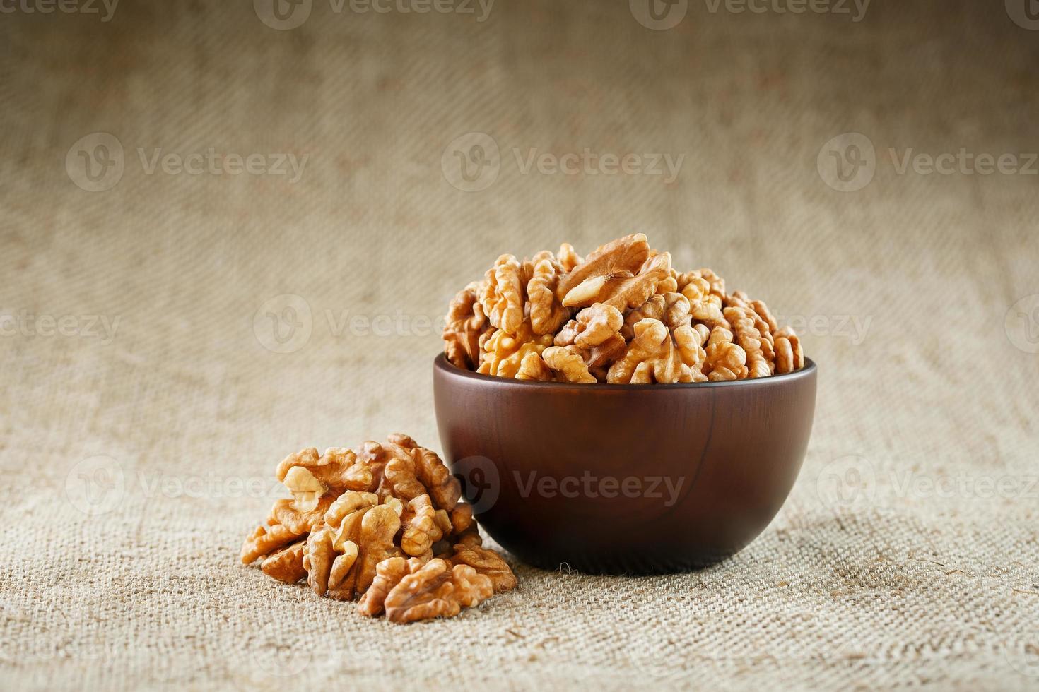 Peeled walnuts in a wooden, dark brown cup on a burlap cloth. photo