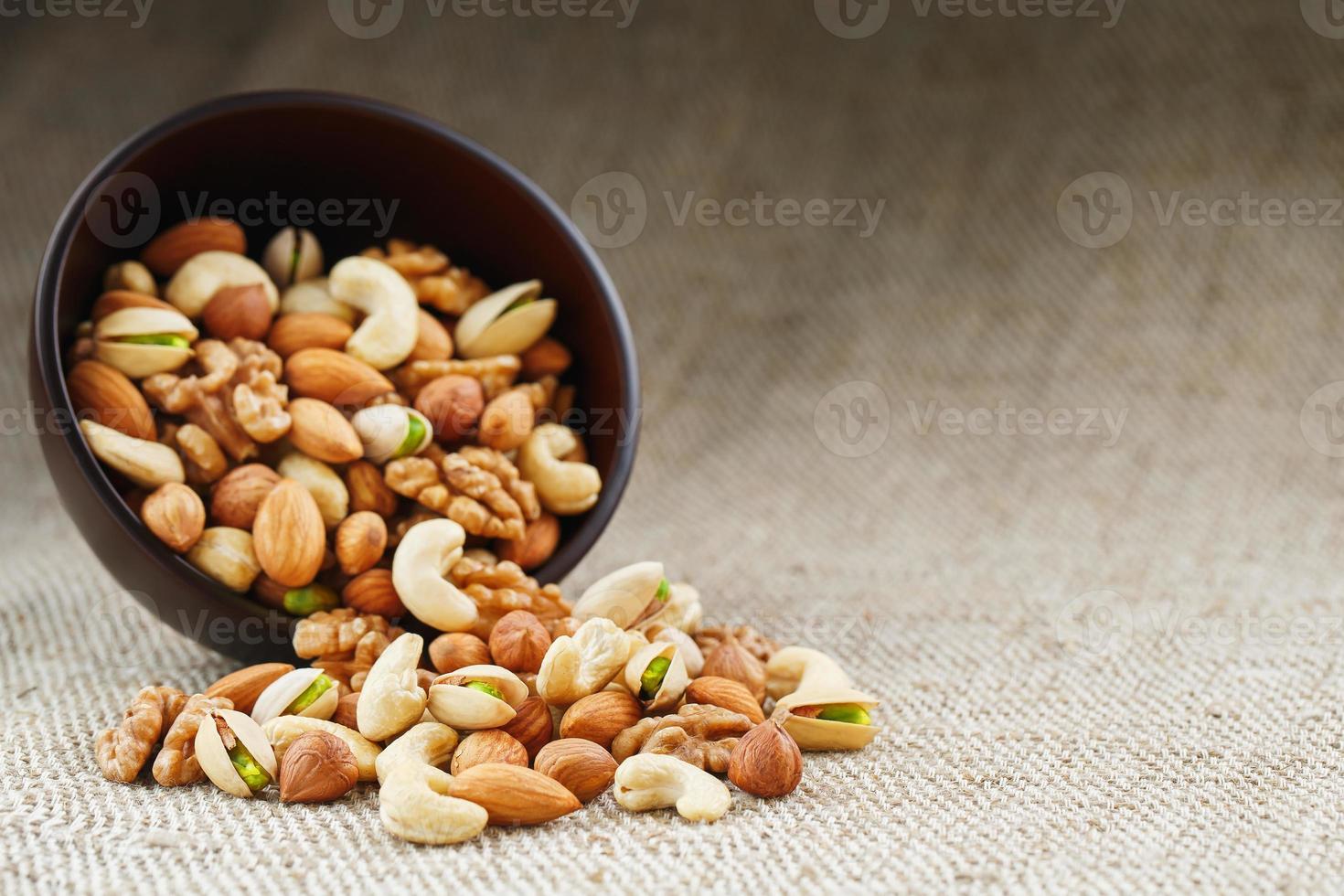 Walnut platter spilled out of the cup on the background of cloth from burlap. Nuts as structure and background, macro. photo