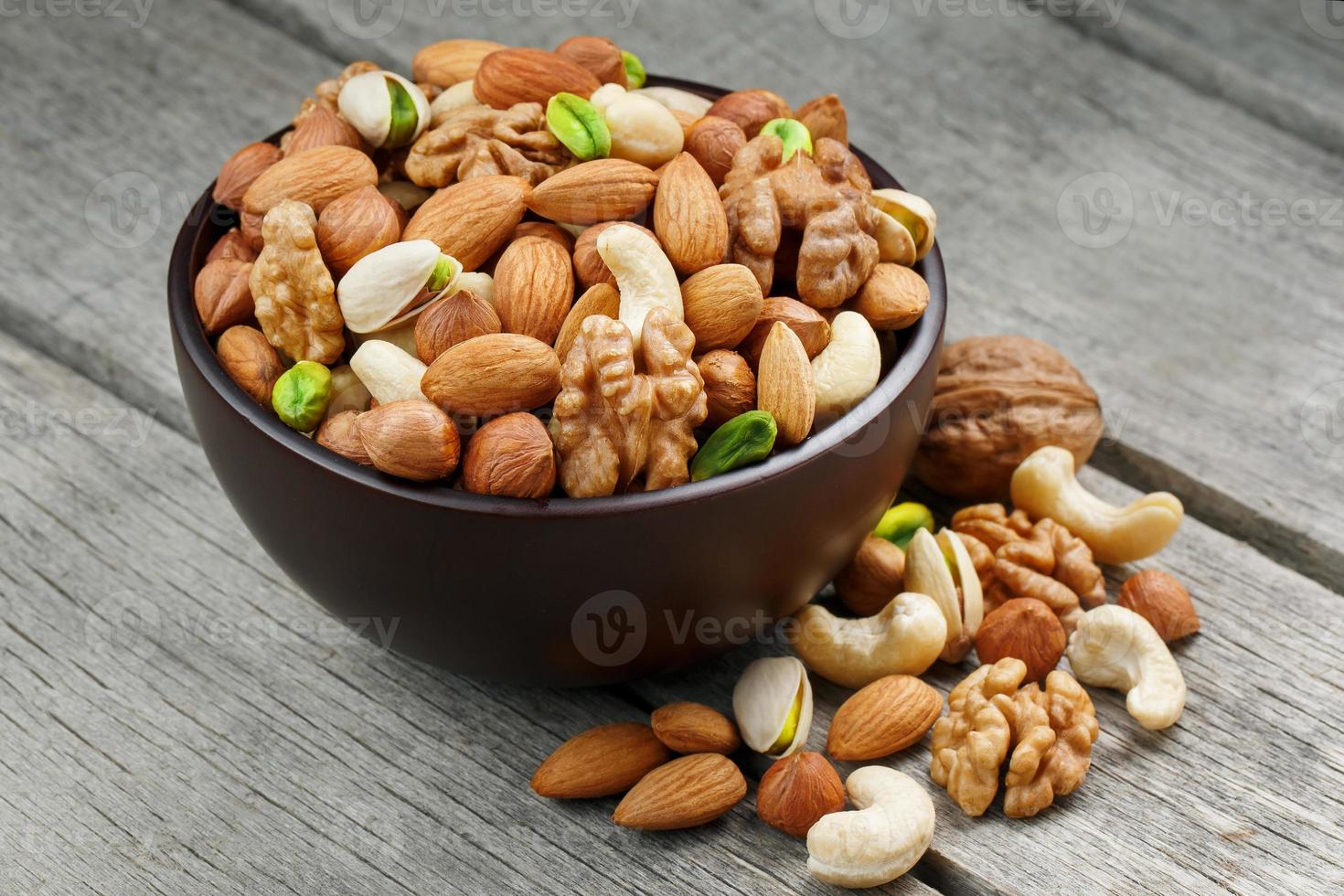 Wooden bowl with mixed nuts on a wooden gray background. Walnut, pistachios, almonds, hazelnuts and cashews, walnut. photo