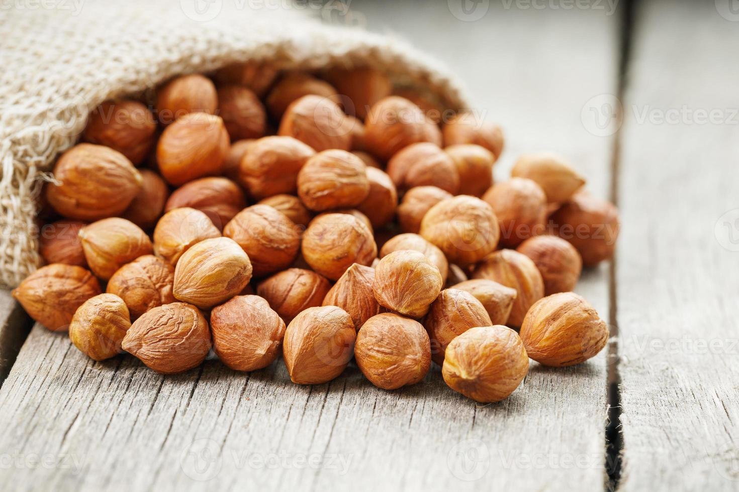 Chiselled hazelnuts in a bag of burlap on a gray wooden table. Organic Fresh Harvested photo