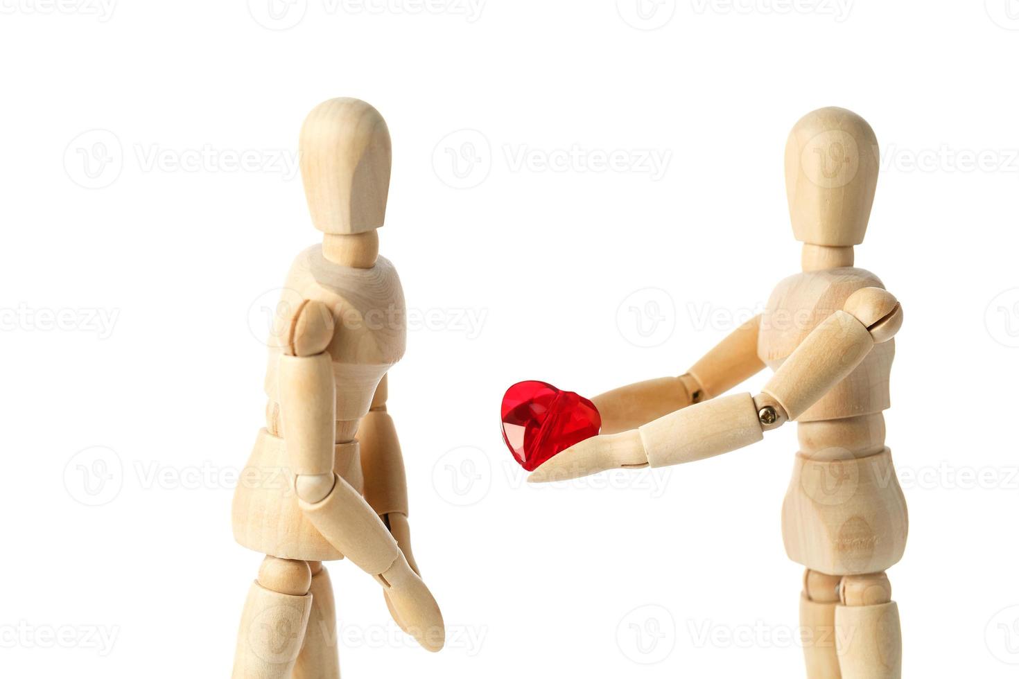 Two wooden figures of a dummy, give a red heart, isolated on a white background - pictures of the theme concepts Love and Valentine's Day. photo