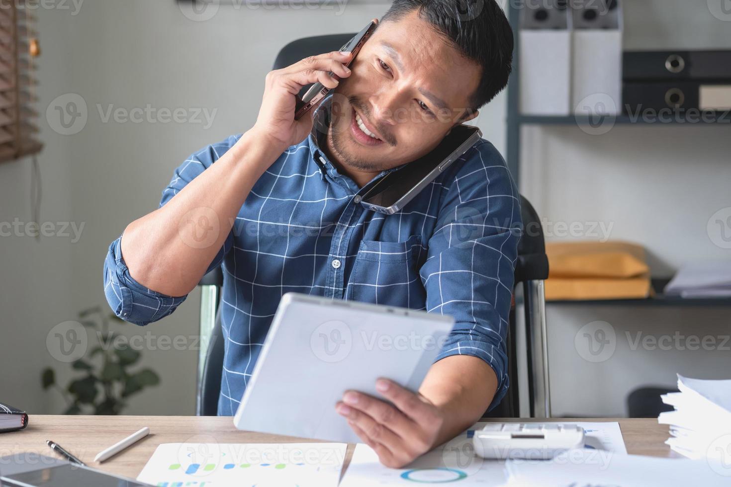 A business man who is using two mobile phones to communicate with