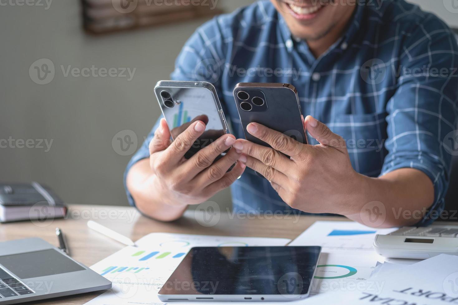 un hombre de negocios que usa dos teléfonos móviles para comunicarse con los clientes es difícil. el concepto está ocupado. foto