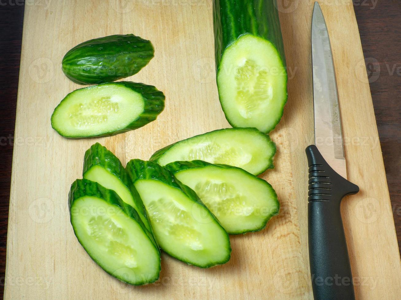 A smooth, medium-sized cucumber cut into slices. Cucumber on a cutting board. Vegetable isolate. Fresh ripe vegetable photo