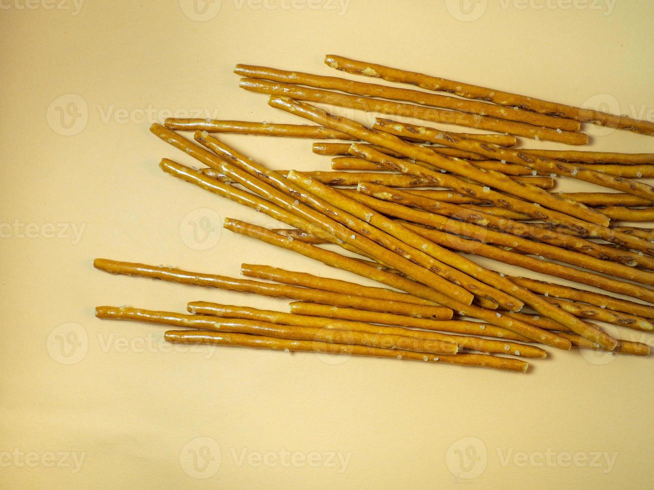 Salted sticks. Confectionery on the table. Salty baked goods. Snack for beer. Dough product on a beige background. Not a healthy diet photo