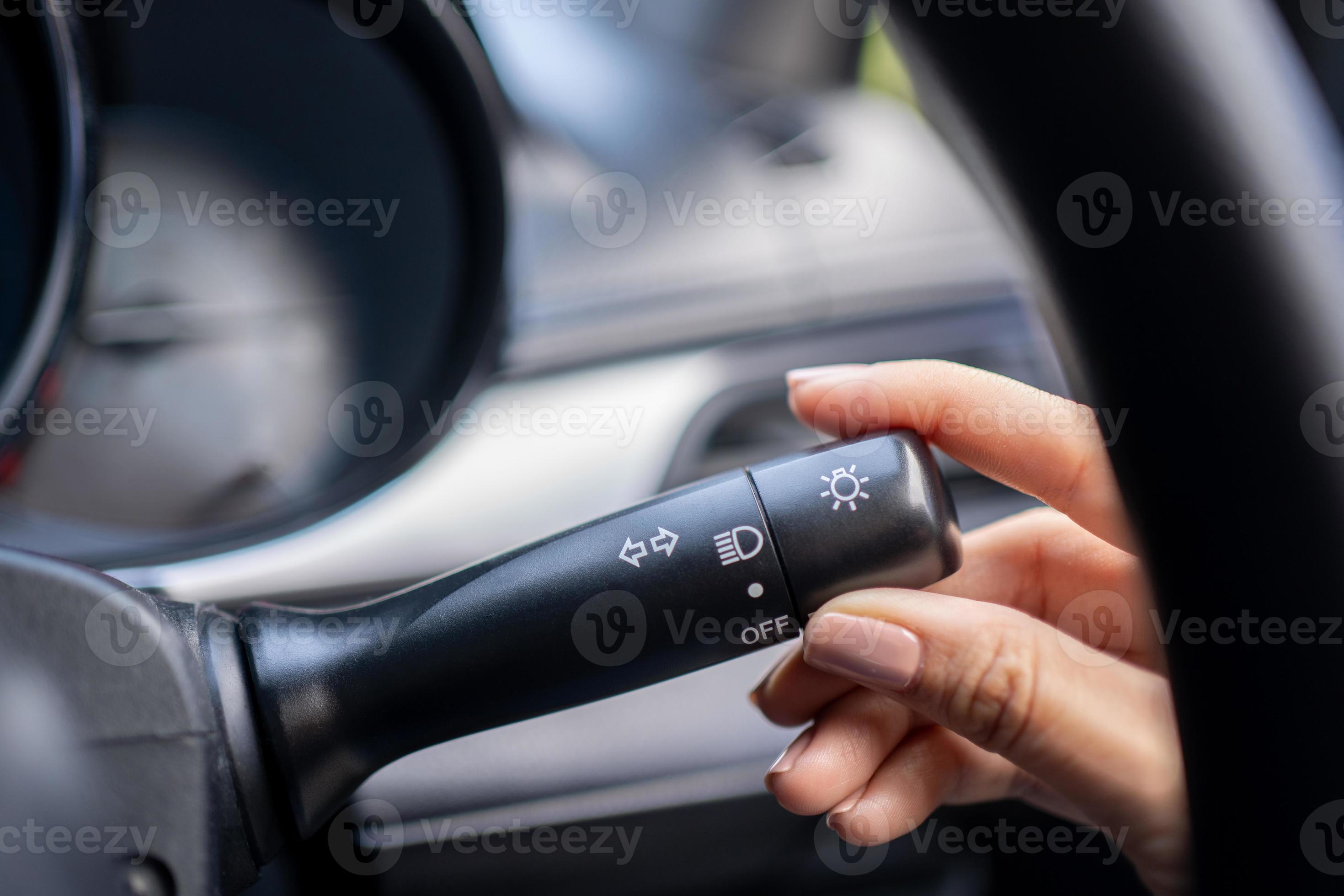 Woman turning on left signal switch, close up shot of her hand