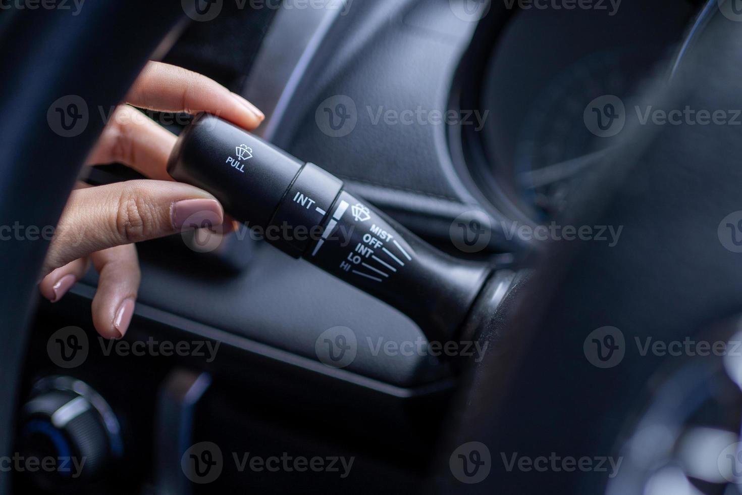 Finger is spinning a wiper control button on the car steering wheel, Close-up and Soft-focus view. photo