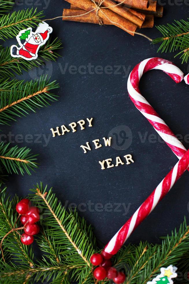 Christmas tree with ornaments and candy on a black background. The inscription Happy New Year photo