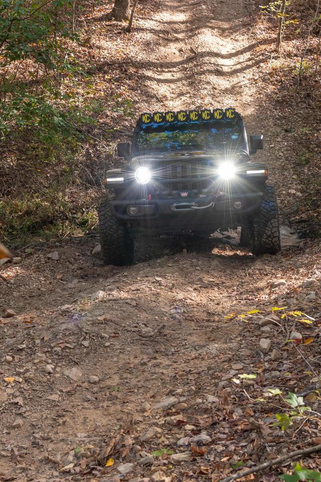 aguas termales, ar, usa, 2022 - bengalas de luz de los faros de un jeep que sube una colina. foto