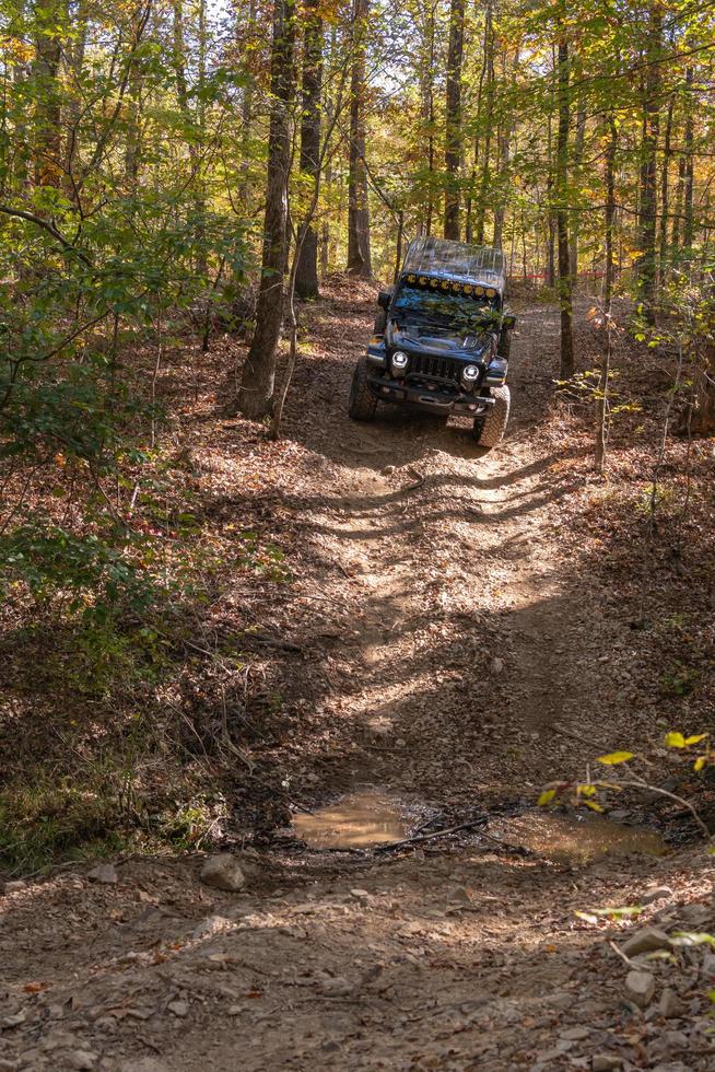 Hot Springs, AR, USA, 2022 - Vertical image of a black Jeep descending a hill on a rutted track. photo