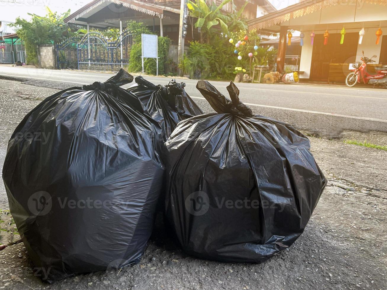 Black garbage bags for general garbage placed in front of the Asian house to wait for the municipal garbage truck to pick it up and leave it. Soft and selective focus. photo