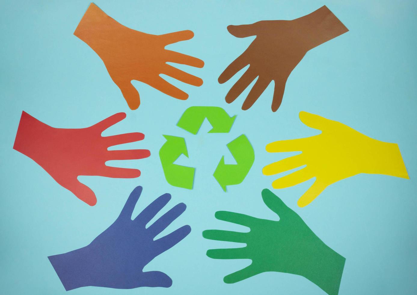 The international recycling sign is a Mobius loop and multicolored hands cut out of paper on a blue background. November 15 - Waste Recycling Day photo