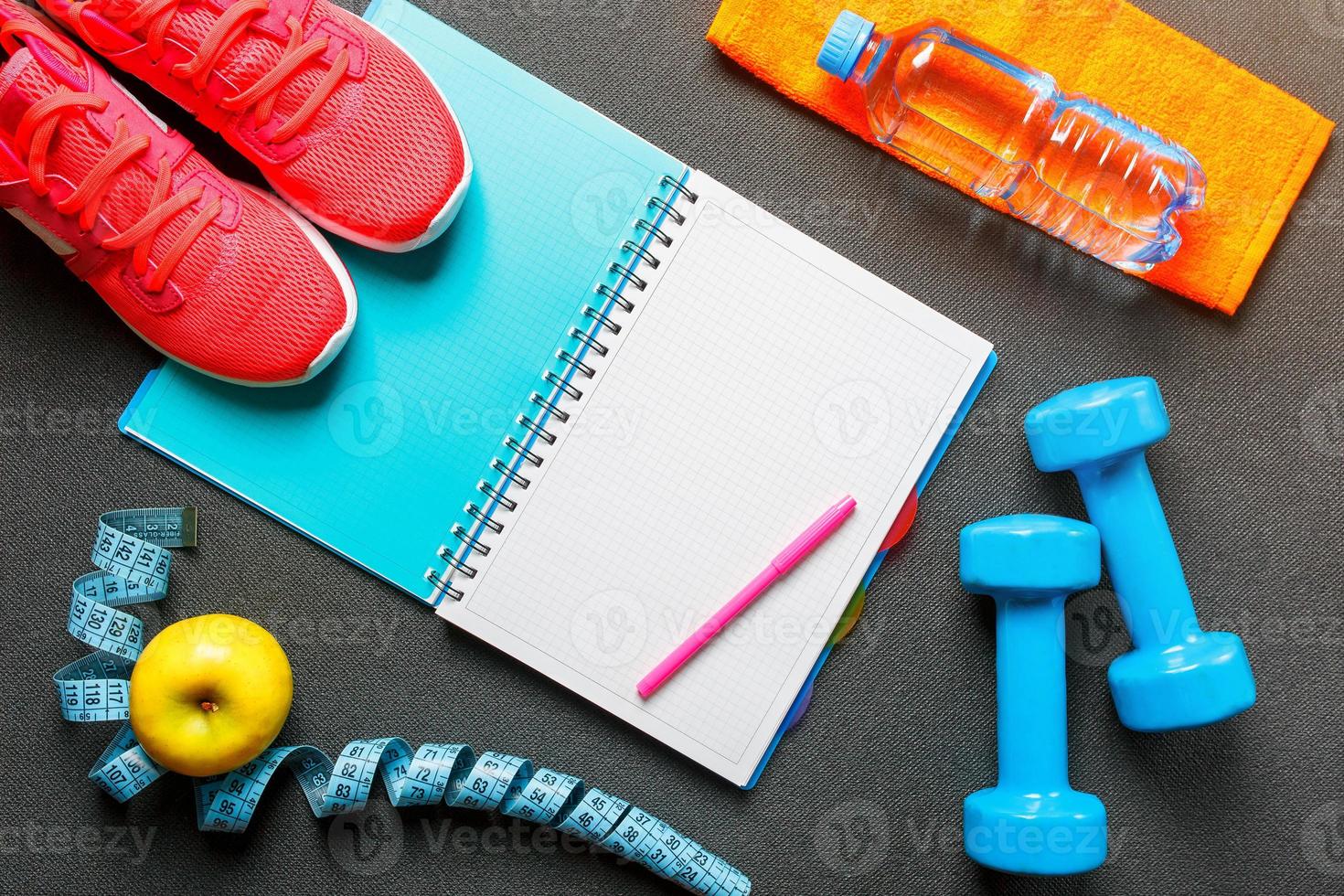 Notepad, a bottle of water, an apple, a skipping rope, dumbbells. Healthy diet, lifestyle, concept of dumbbells, exercise photo