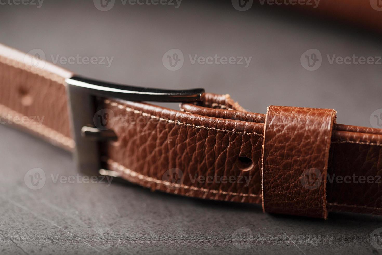 A brown belt bag made of textured brown leather on a black stone background. Elegant fanny pack brown bag with a zipper photo