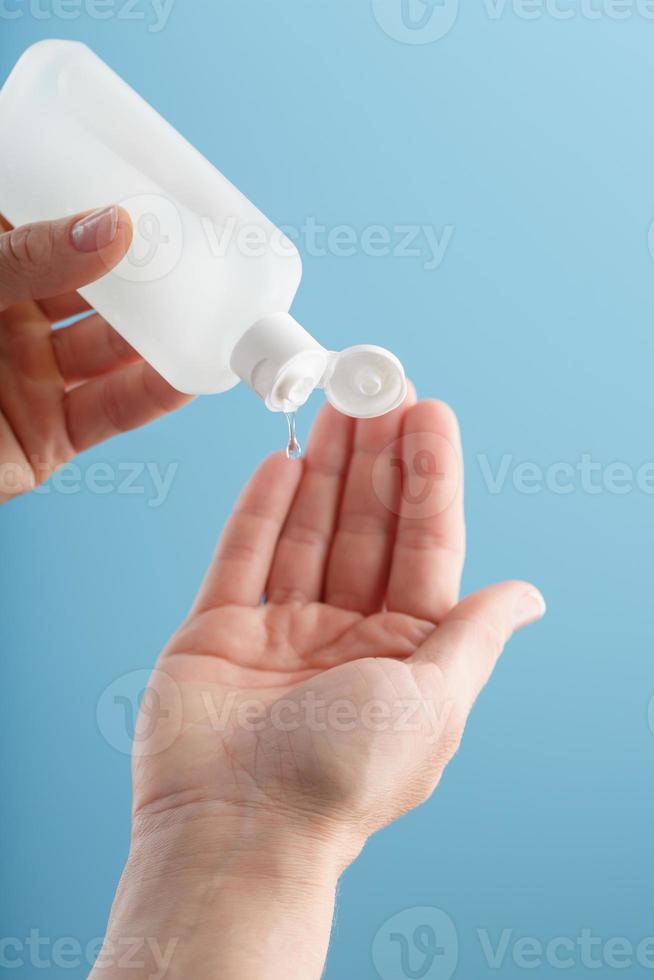 A bottle of Disinfectant gel in your hands on a blue background. Antiseptic treatment of hands from bacteria Sanitizer. photo