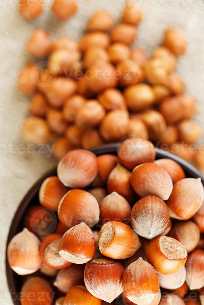 Peeled hazelnuts in a wooden, dark brown cup on a burlap cloth. Super Food, Raw. photo