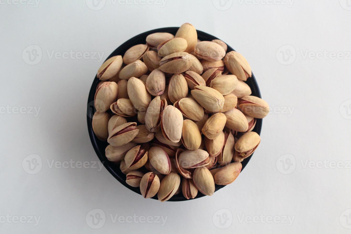 pistacho en nueces de cáscara en un recipiente sobre fondo blanco. foto