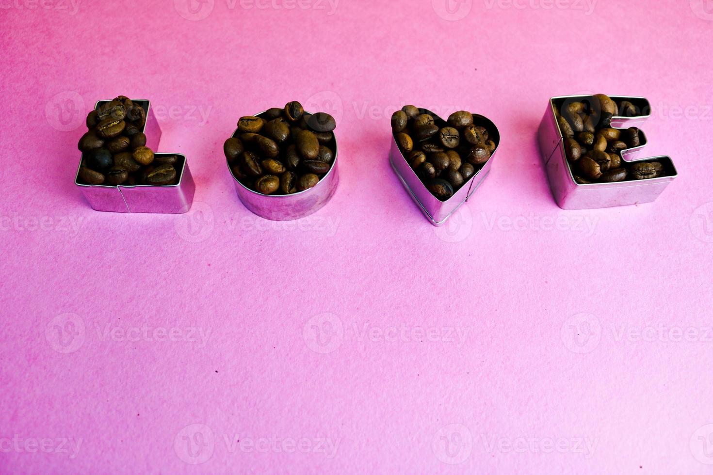 Beautiful texture with the word love for valentine's day inscription made from roasted selected brown natural aromatic Arabica coffee beans, robusta Copy space, flat lay, pink purple background photo